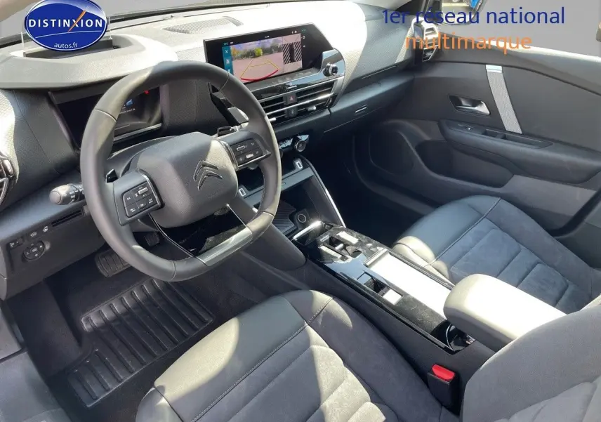 Intérieur moderne de la Citroën C4 2024, vue côté conducteur, sièges cuir noir et écran tactile avec caméra de recul.