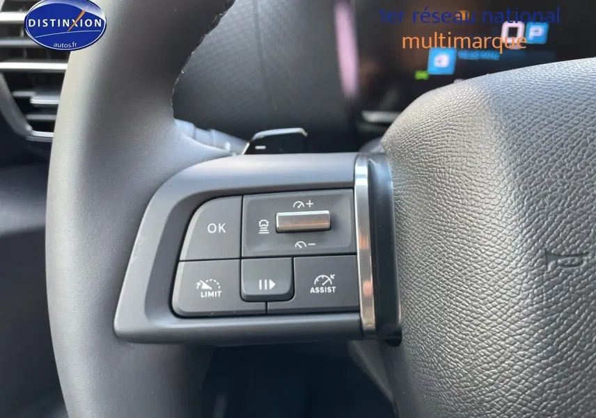 Gros plan sur les commandes au volant à gauche du Citroën C4 gris platinium 2024, boutons de régulateur et assistant de conduite.