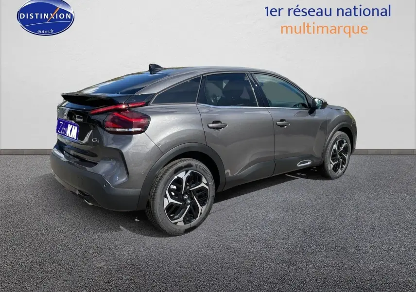 Vue 3/4 arrière droite d'une Citroën C4 2024 gris platinium métal avec jantes noires et toit noir contrasté.
