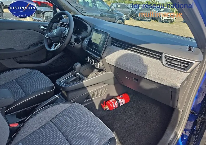 Intérieur avant droit de Renault Clio V bleu iron 2025, avec tableau de bord moderne et siège tissu gris.