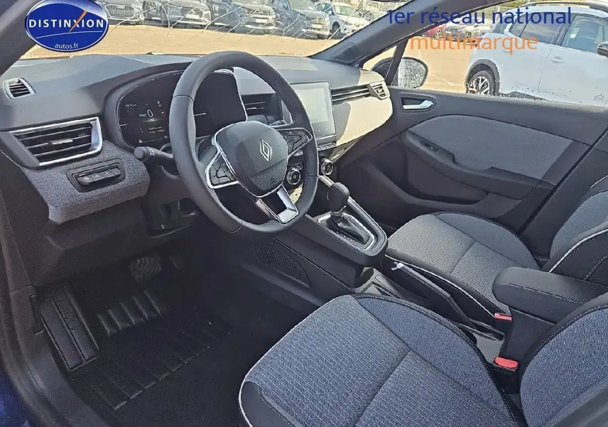 Intérieur avant droit de la Renault Clio V 1.6 e-tech 145 techno, sièges tissu bleu et console centrale avec boîte auto.