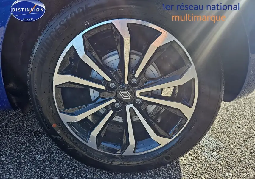 Gros plan sur la jante alu noire et argentée d'une Renault Clio V Bleu Iron, avec pneu Bridgestone visible.