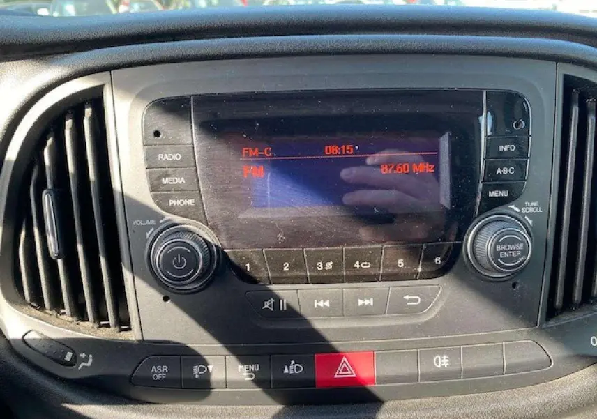 Vue rapprochée du tableau de bord du Fiat Doblo 2017 avec autoradio et commandes climatisation visibles.