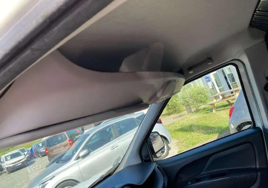 Vue intérieure côté conducteur du Fiat Doblo blanc 2017, montrant le tableau de bord et la portière avec vitre baissée.