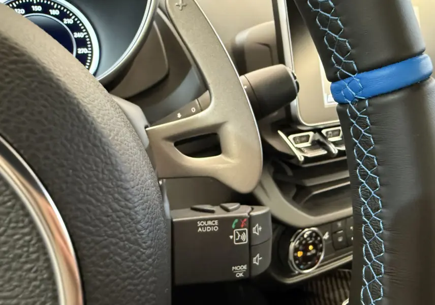 Gros plan sur le volant cuir noir avec surpiqûres bleues de l'Alpine A110 Legende 2019, tableau de bord partiel visible.