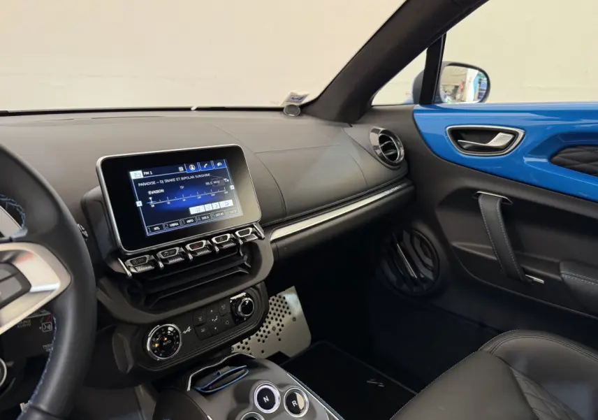 Intérieur côté passager de l'Alpine A110 Légende 2019 bleu, avec écran tactile central et finitions cuir noires.