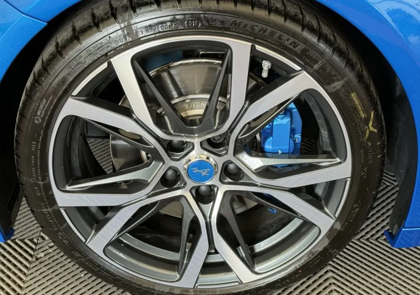 Gros plan sur la jante alliage à dix branches de l'ALPINE A110 Legende bleue avec étrier de frein bleu visible.
