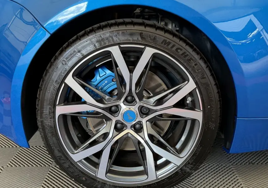 Gros plan sur la roue avant droite bleue d'une Alpine A110 Legende 2019, avec étrier de frein bleu et jante argentée.