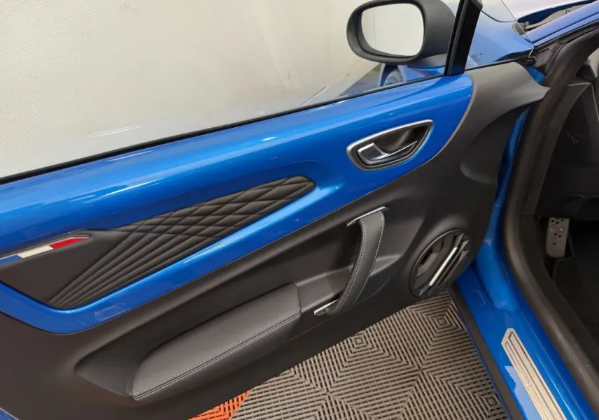 Détail de la porte côté conducteur bleu de l'Alpine A110 Légende 2019 avec surpiqûres et poignée en cuir.