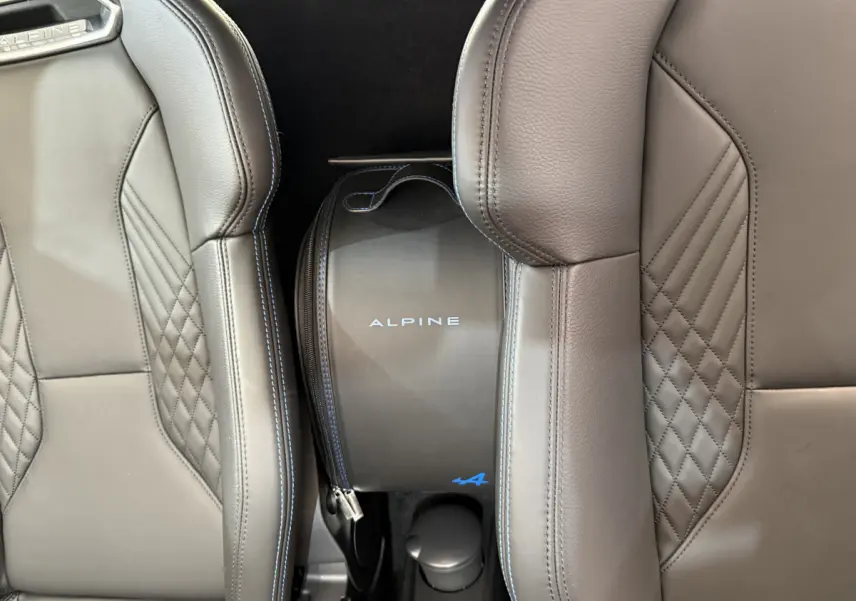 Gros plan sur la mallette Alpine bleue entre les sièges en cuir gris au design matelassé de l'A110 Legende 2019.