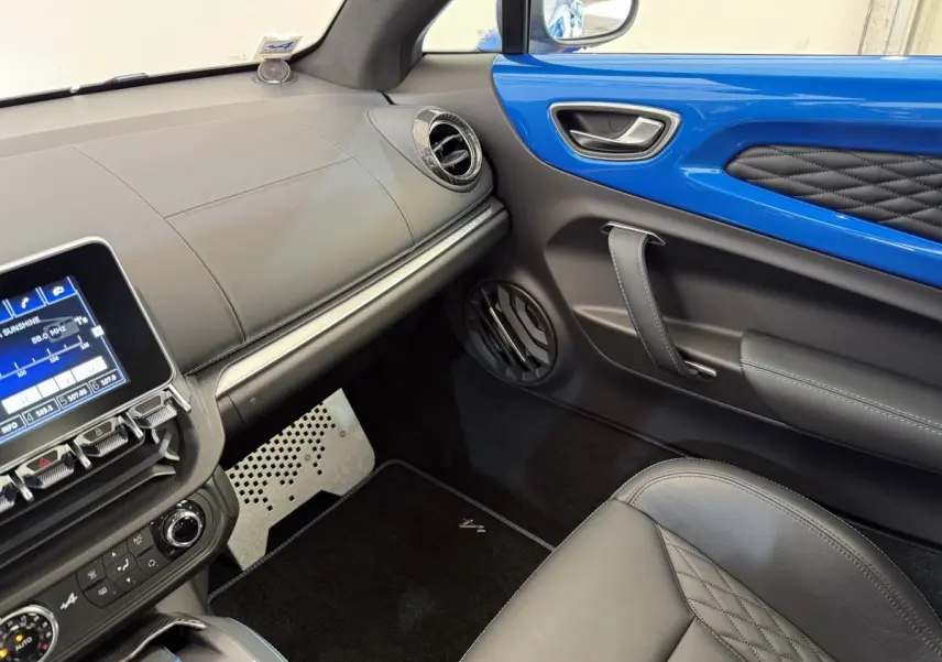 Vue intérieure côté passager de l'Alpine A110 Legende 2019 avec tableau de bord noir et insert bleu brillant sur la porte.