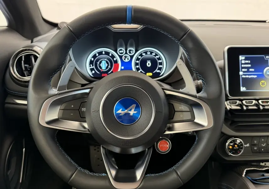 Vue frontale du volant cuir noir avec logo Alpine bleu et bouton rouge Sport sur le tableau de bord de l'Alpine A110 Legende 2019.