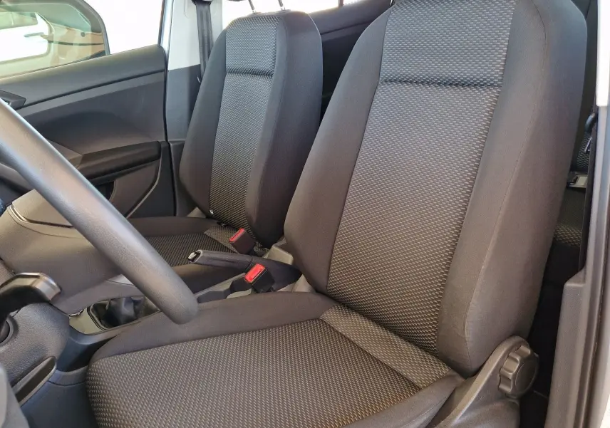 Vue intérieure côté conducteur du Volkswagen T-Cross 2019, sièges tissu gris foncé avec accoudoir central visible.