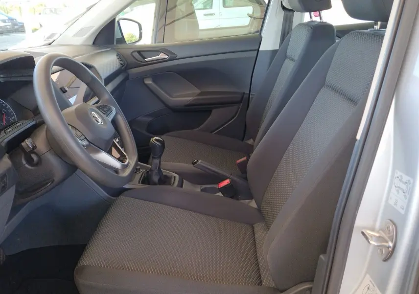 Vue intérieure côté conducteur du Volkswagen T-Cross argent métal 2019, montrant sièges et volant avec boîte manuelle.