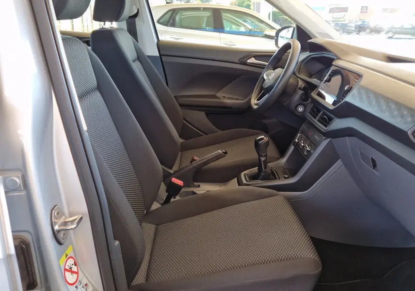 Intérieur côté conducteur du Volkswagen T-Cross argent métal 2019, sièges noirs et tableau de bord moderne avec boîte manuelle.