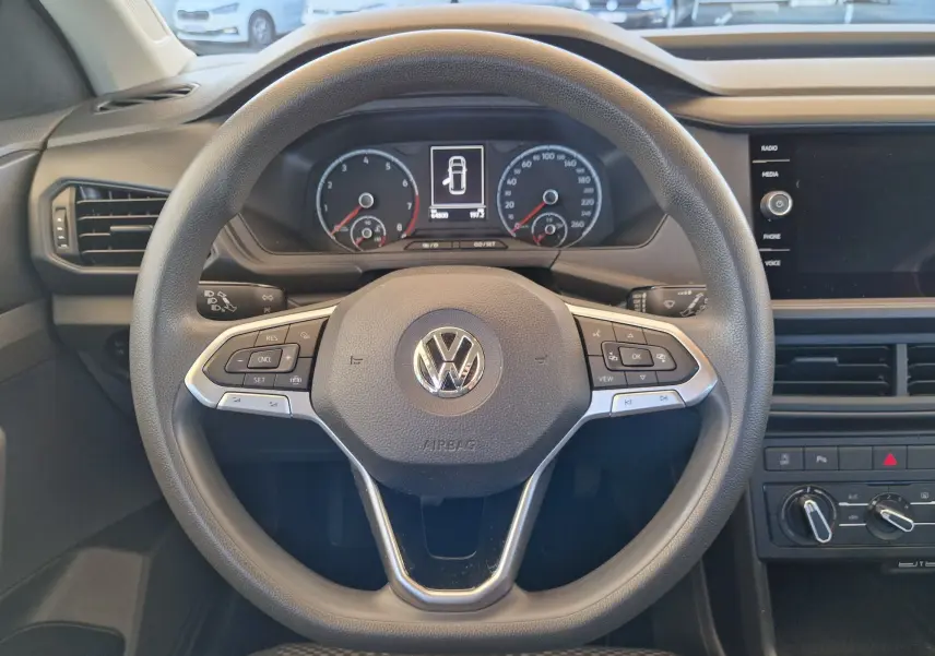 Vue rapprochée du volant multifonction d'un Volkswagen T-Cross 2019, avec tableau de bord numérique et commandes intégrées.