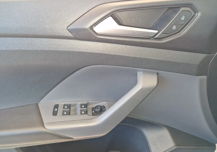 Vue rapprochée de la porte côté conducteur du Volkswagen T-Cross argent métal avec commandes de vitres et verrouillage.
