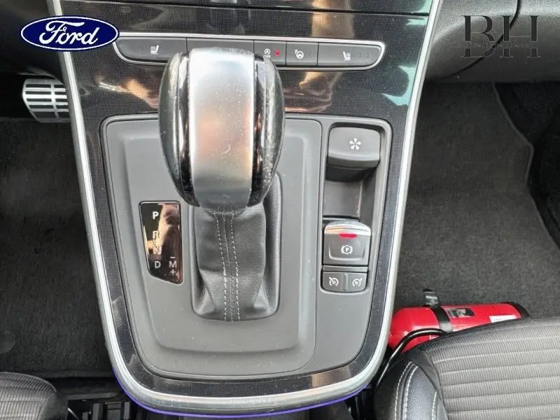 Gros plan sur le levier de vitesses automatique et commandes du frein à main électrique dans l'habitacle noir du Renault Grand Scenic.