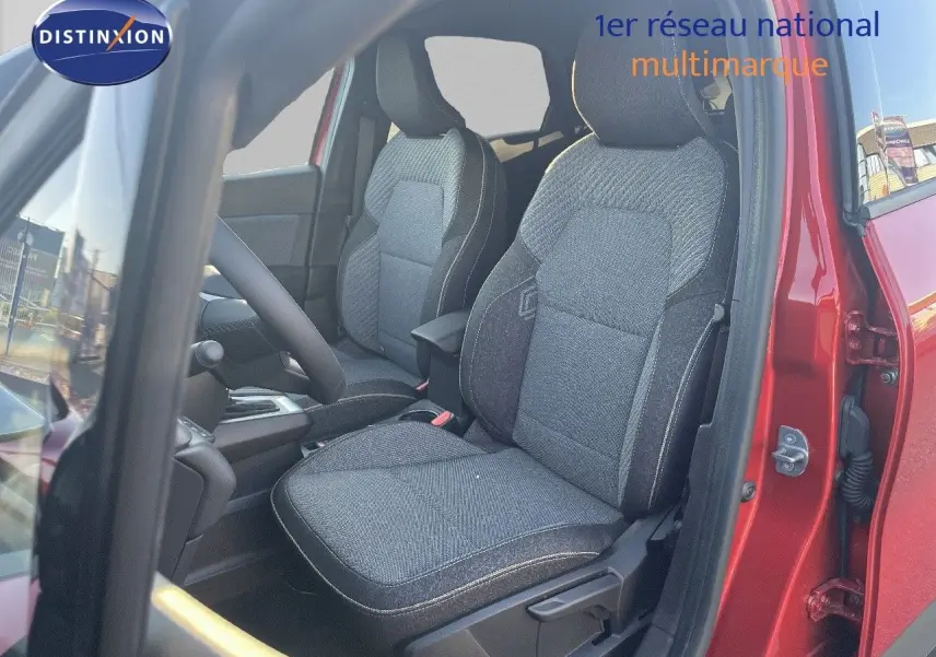 Vue intérieure côté conducteur du Renault Captur rouge passion, mettant en valeur les sièges en tissu gris foncé.