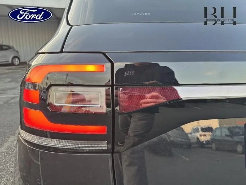 Gros plan sur le feu arrière gauche d’un Volkswagen T-Cross noir intense nacré avec éclairage LED allumé.