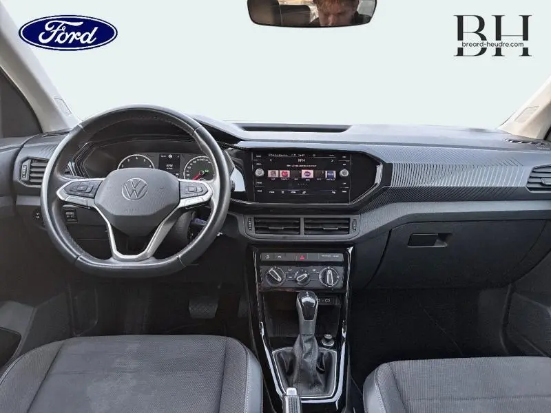 Vue intérieure avant du Volkswagen T-Cross 2022 noir intense nacré, avec tableau de bord et volant multifonction en cuir.