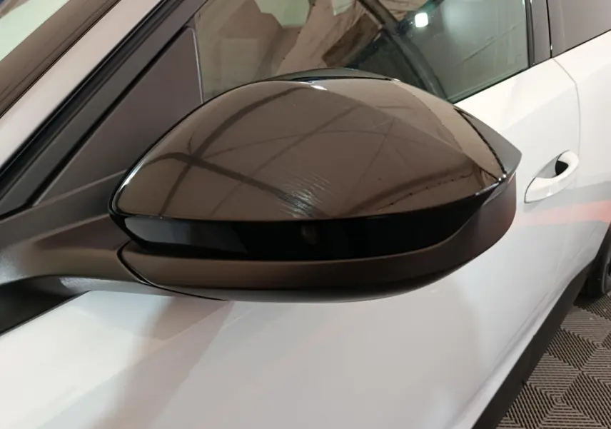 Gros plan sur le rétroviseur noir côté gauche du Peugeot 3008 blanc, avec portière et poignée visibles.