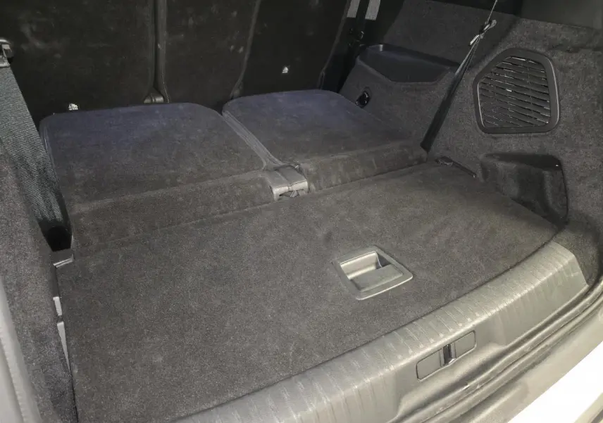 Vue rapprochée du coffre du Peugeot 5008 blanc 2025 avec banquette arrière rabattue et revêtement noir.