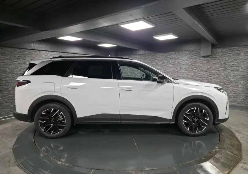 Peugeot 5008 blanc vue de profil côté gauche, avec jantes alliage noires et toit noir brillant.