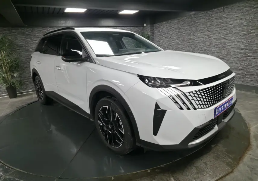 Peugeot 5008 blanc en 3/4 avant droit, avec calandre noire à motif géométrique et jantes alliage noires.