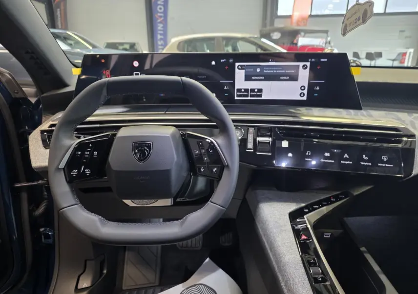 Vue intérieure centrée sur le volant compact cuir noir et l'écran panoramique du tableau de bord du Peugeot 3008 bleu.