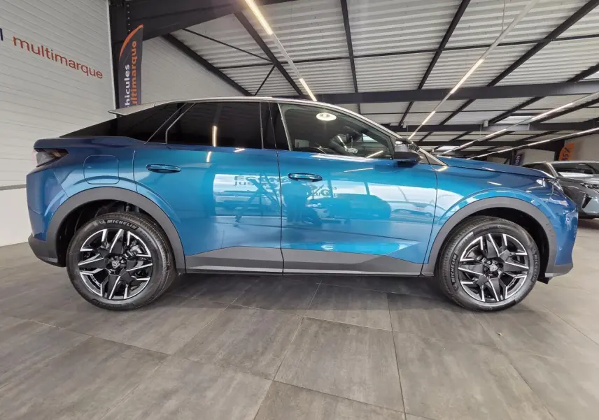 Profil droit du Peugeot 3008 hybride bleu métallisé avec jantes alliage 18 pouces et protections noires grainées.