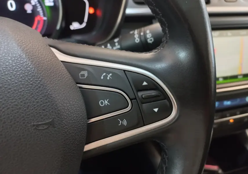 Gros plan sur les commandes multifonctions en cuir du volant du Renault Kadjar Intens Energy TCe 130 EDC, avec écran tactile en arrière-plan.