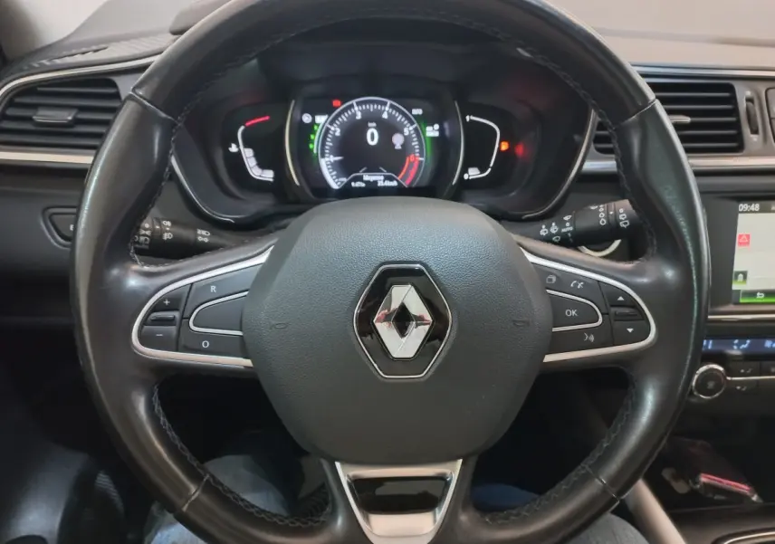 Vue intérieure centrée sur le volant cuir noir du Renault Kadjar Intens avec tableau de bord et écran tactile visible à droite.