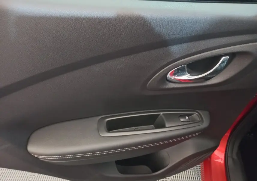 Détail de la porte intérieure côté conducteur du Renault Kadjar rouge, avec poignée chrome et bouton de verrouillage.