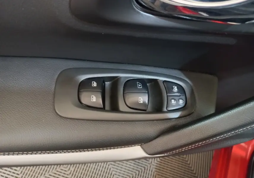 Gros plan sur les commandes de lève-vitres et verrouillage sur la porte côté conducteur d’un Renault Kadjar rouge.
