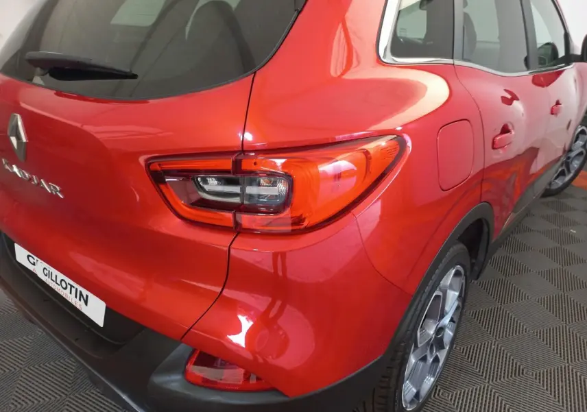 Vue 3/4 arrière droite du Renault Kadjar rouge brillant, avec feux arrière distinctifs et jantes alliage visibles.