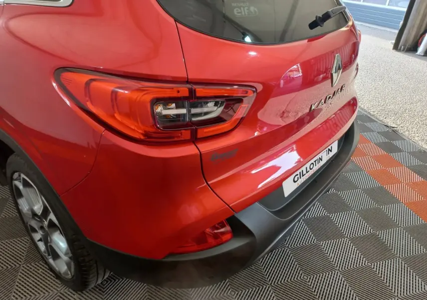 Vue 3/4 arrière droite d'un Renault Kadjar rouge avec feux arrière LED et logo visible sur un sol à motifs.
