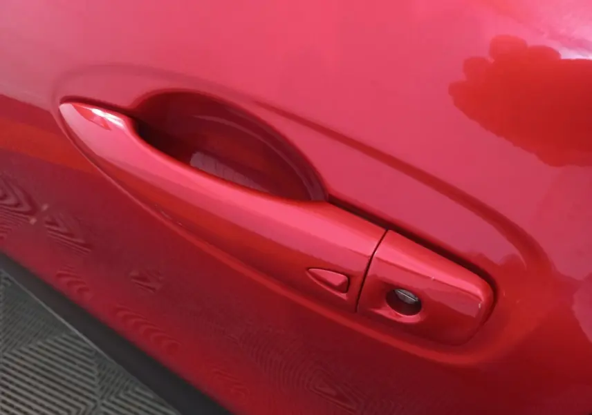 Poignée de porte côté gauche rouge vif du Renault Kadjar Intens Energy TCe 130 EDC, vue en gros plan.
