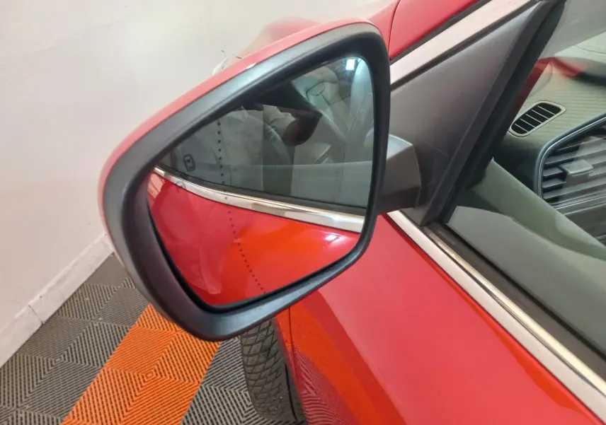 Rétroviseur côté gauche d’un Renault Kadjar rouge, vue rapprochée avec partie de la portière et intérieur visible.