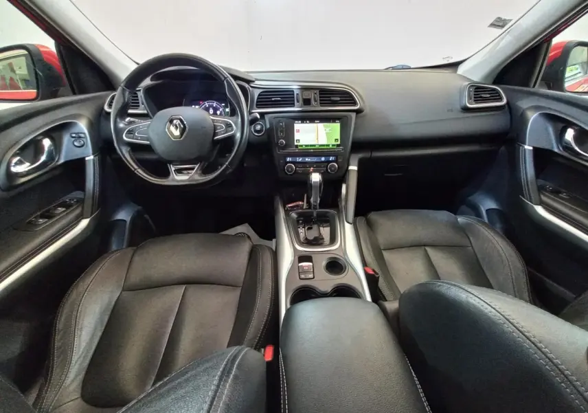 Vue intérieure avant du Renault Kadjar Intens, montrant tableau de bord noir avec écran tactile et sièges en cuir noir.