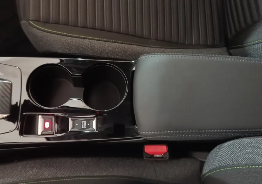 Vue rapprochée de la console centrale noire avec frein à main électrique et bouton Drive Mode sur Peugeot 208 électrique gris clair.