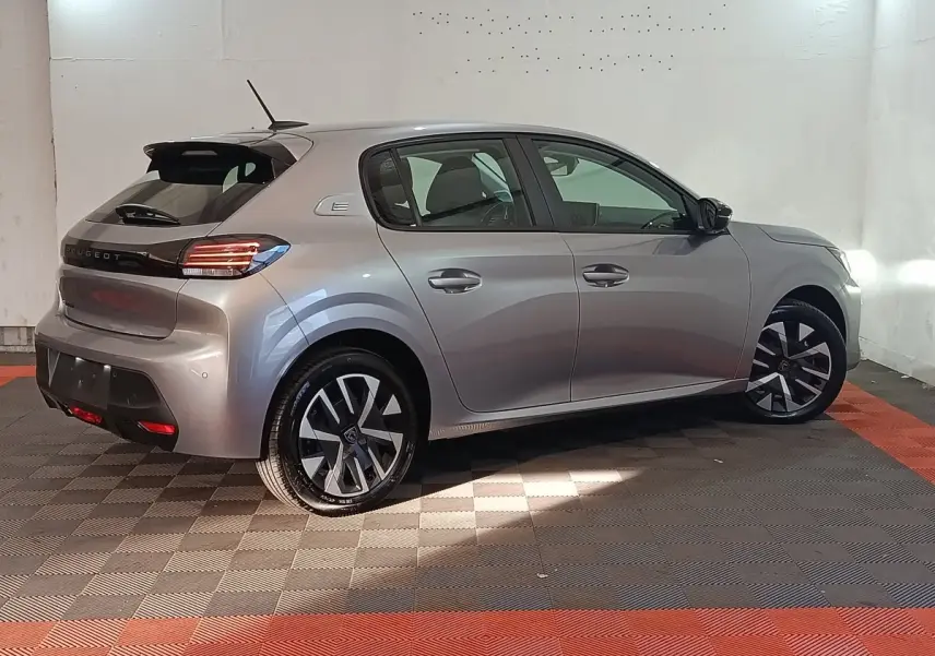 Peugeot 208 électrique gris clair vue de profil côté droit, avec jantes alliage et feux arrière LED distinctifs.