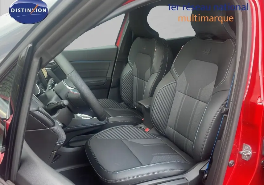 Vue intérieure côté conducteur du Renault Captur rouge passion, mettant en valeur les sièges noirs en cuir avec surpiqûres bleues.