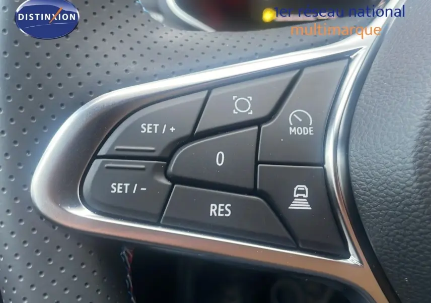 Gros plan sur les commandes au volant en cuir perforé noir du Renault Captur E-Tech hybride rouge passion toit noir.