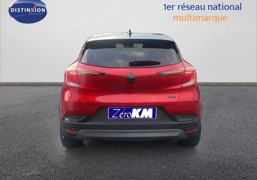 Vue arrière du Renault Captur E-Tech hybride rouge passion avec toit noir, feux LED allumés et plaque Zéro KM.