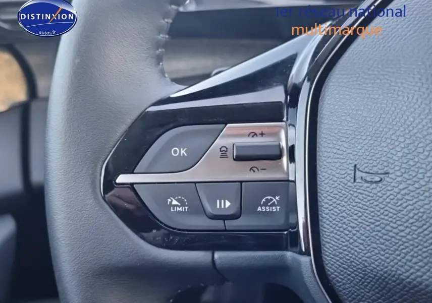 Gros plan sur les commandes gauche du volant cuir noir du Peugeot 408 gris sellenium e, avec boutons de régulateur et assistances.