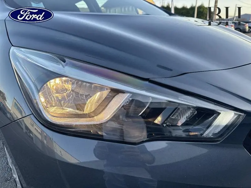 Gros plan sur le phare avant droit gris acier d'une Nissan Micra 2018 avec éclairage allumé.