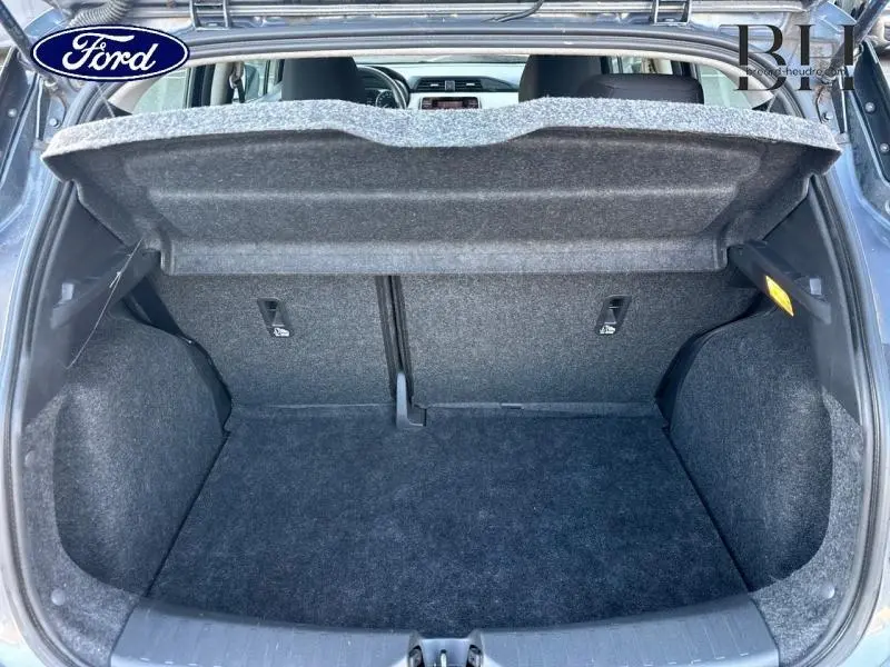 Coffre ouvert vu de l'arrière d'une Nissan Micra gris acier, montrant l'espace de chargement et la tablette cache-bagages.