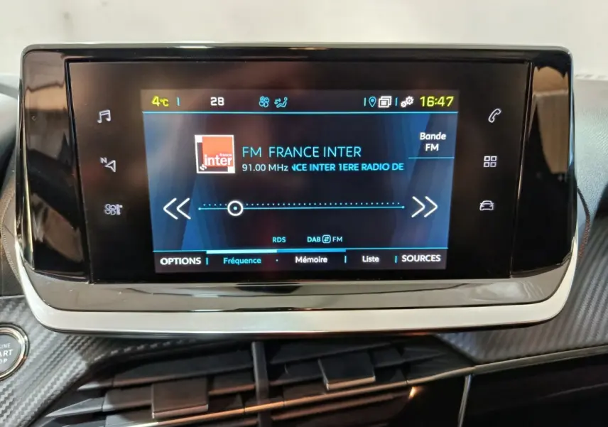 Écran tactile central du tableau de bord de la Peugeot 208 électrique Active Business, affichant la radio FM.