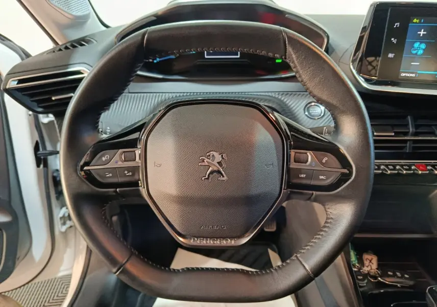 Vue rapprochée du volant cuir multifonctions noir du Peugeot 208 électrique Active Business 2020 avec tableau de bord numérique.